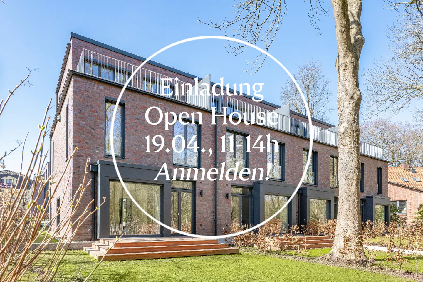 Brick building with large windows and an open house invitation. Lawn and trees surround the property.