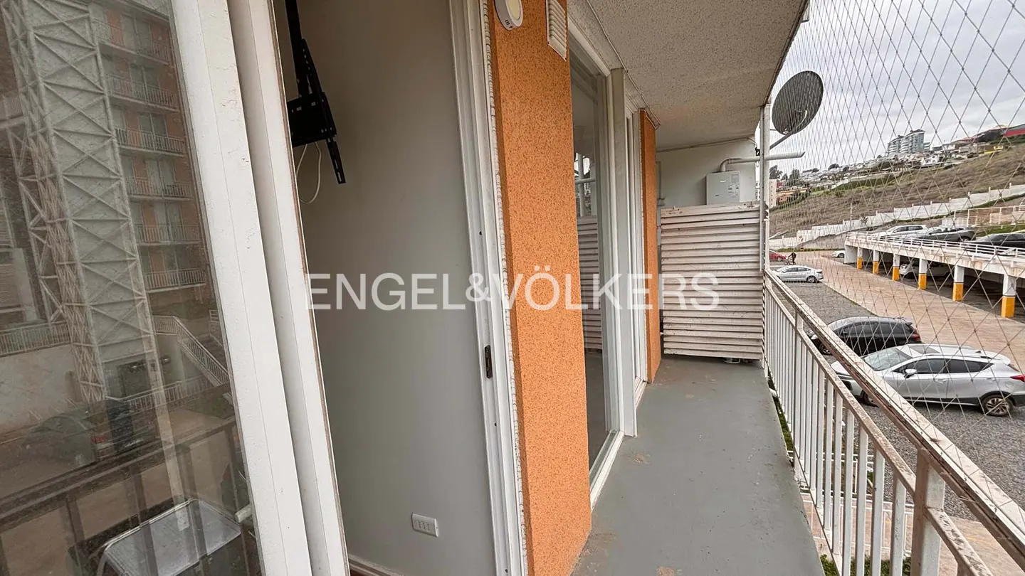 Balcony view with white railings, a satellite dish, and a parking lot with cars. Orange exterior wall and Engel & Völkers logo visible.