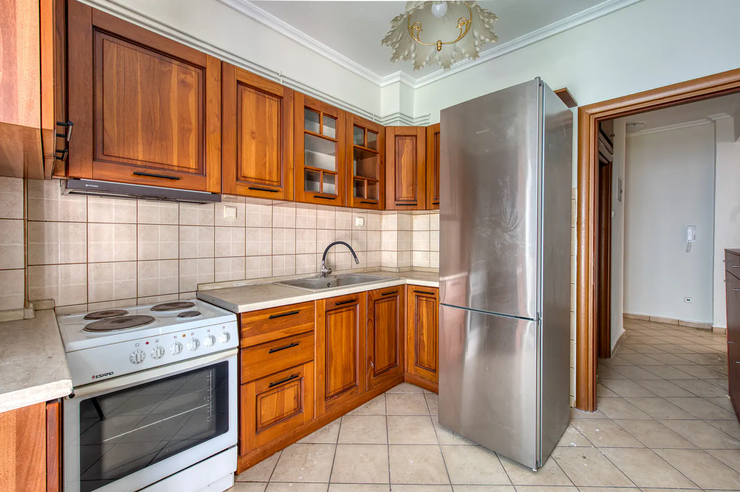 A kitchen with wood cabinets, a white stove, and a stainless steel refrigerator.