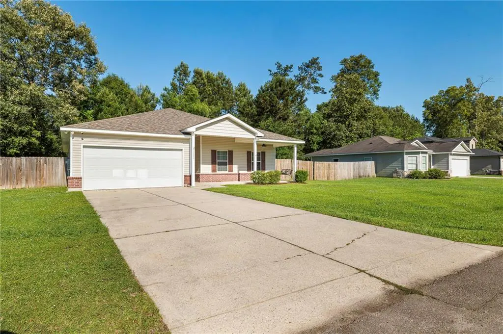 Beige single-story house with a white garage door and a long concrete driveway on a sunny day.