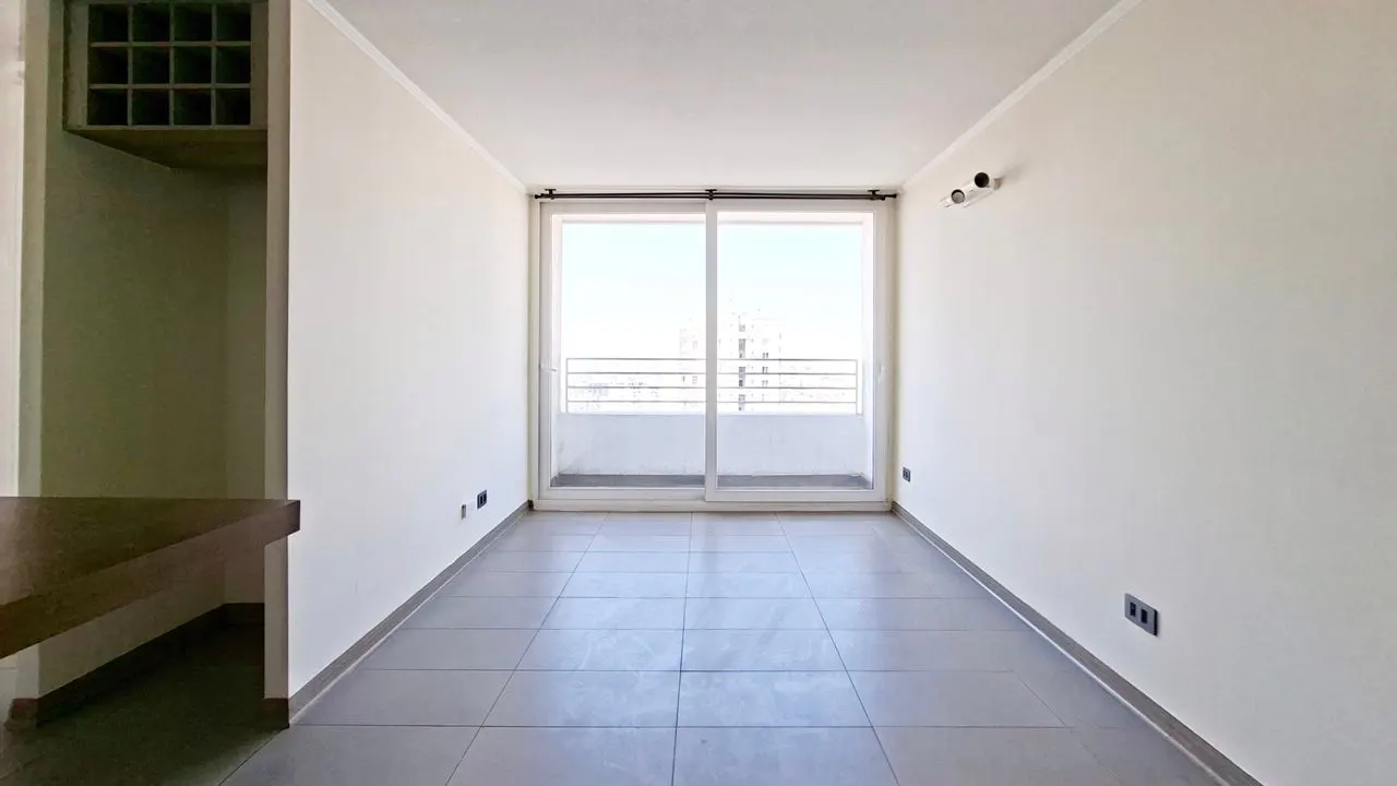 Empty room with gray tile floor, white walls, and sliding glass doors to a balcony with a city view.