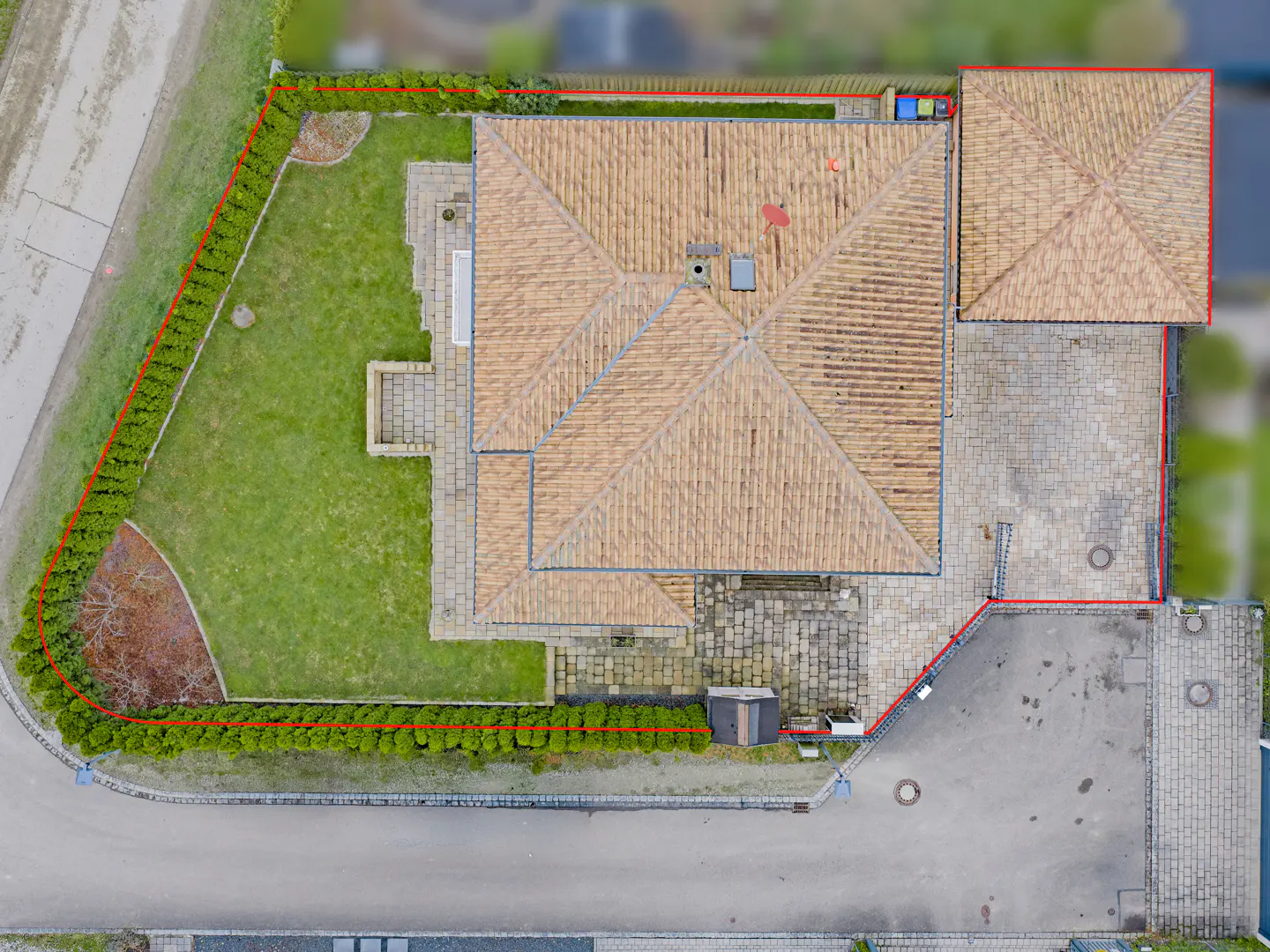 Aerial view of a house with a brown tile roof, green lawn, and a red boundary line.