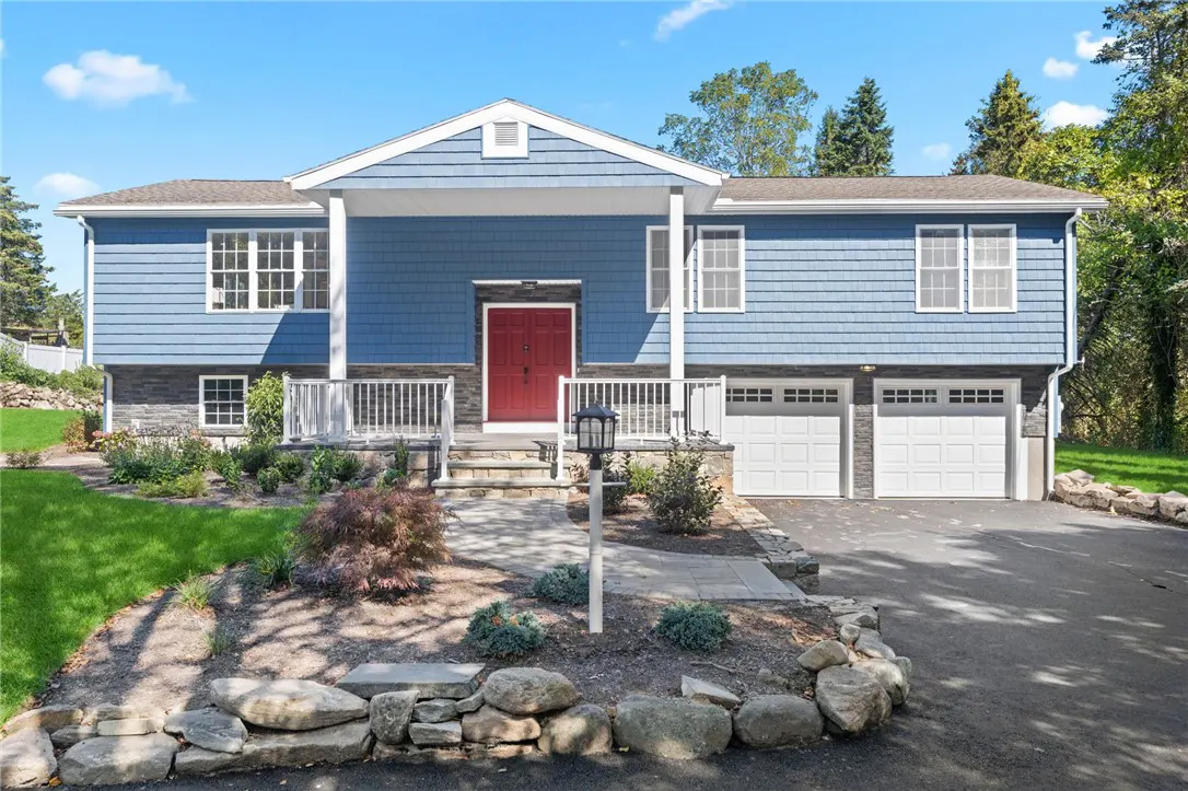 Two-story blue house with a red door, white trim, and a two-car garage. A stone walkway leads to the front porch.