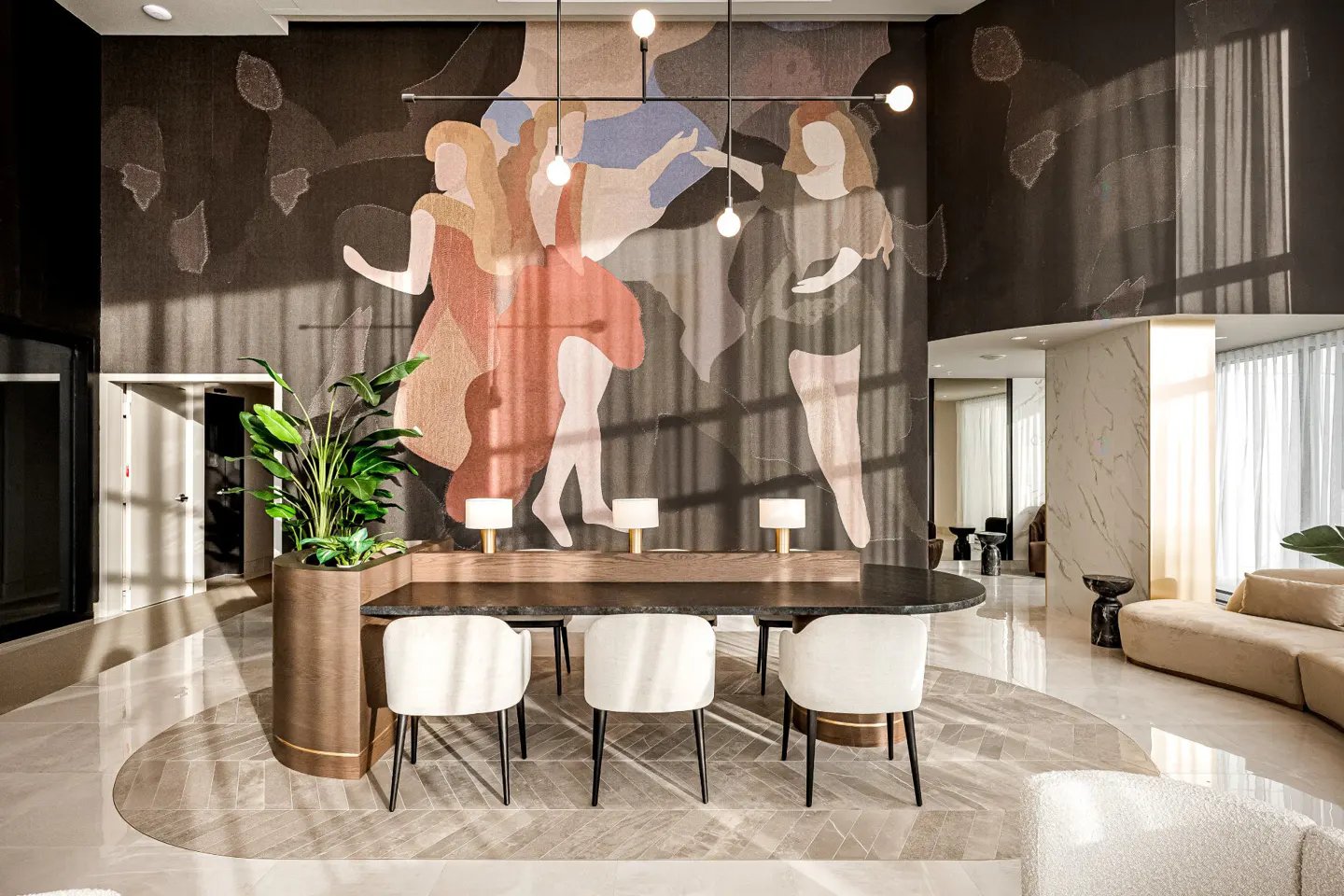 Modern lobby with a dark wood reception desk, white chairs, and a large mural of dancing figures on the wall.