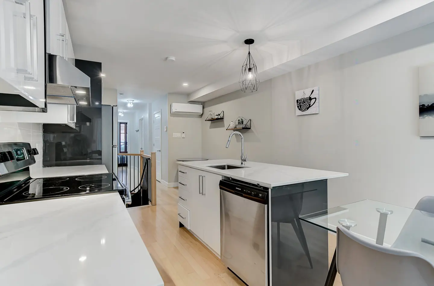 Modern kitchen with white cabinets, stainless steel appliances, a quartz island, and a glass dining table.