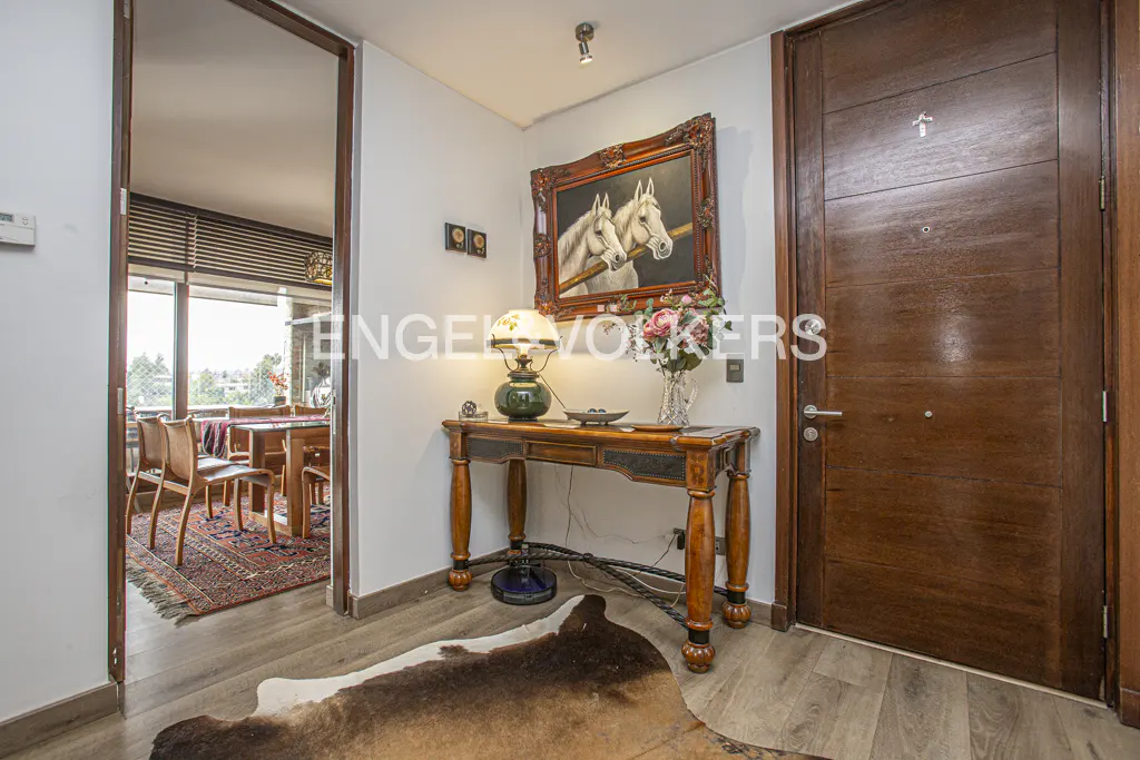 Entryway with a wooden door, console table with a lamp, horse painting, and a glimpse into the dining area.