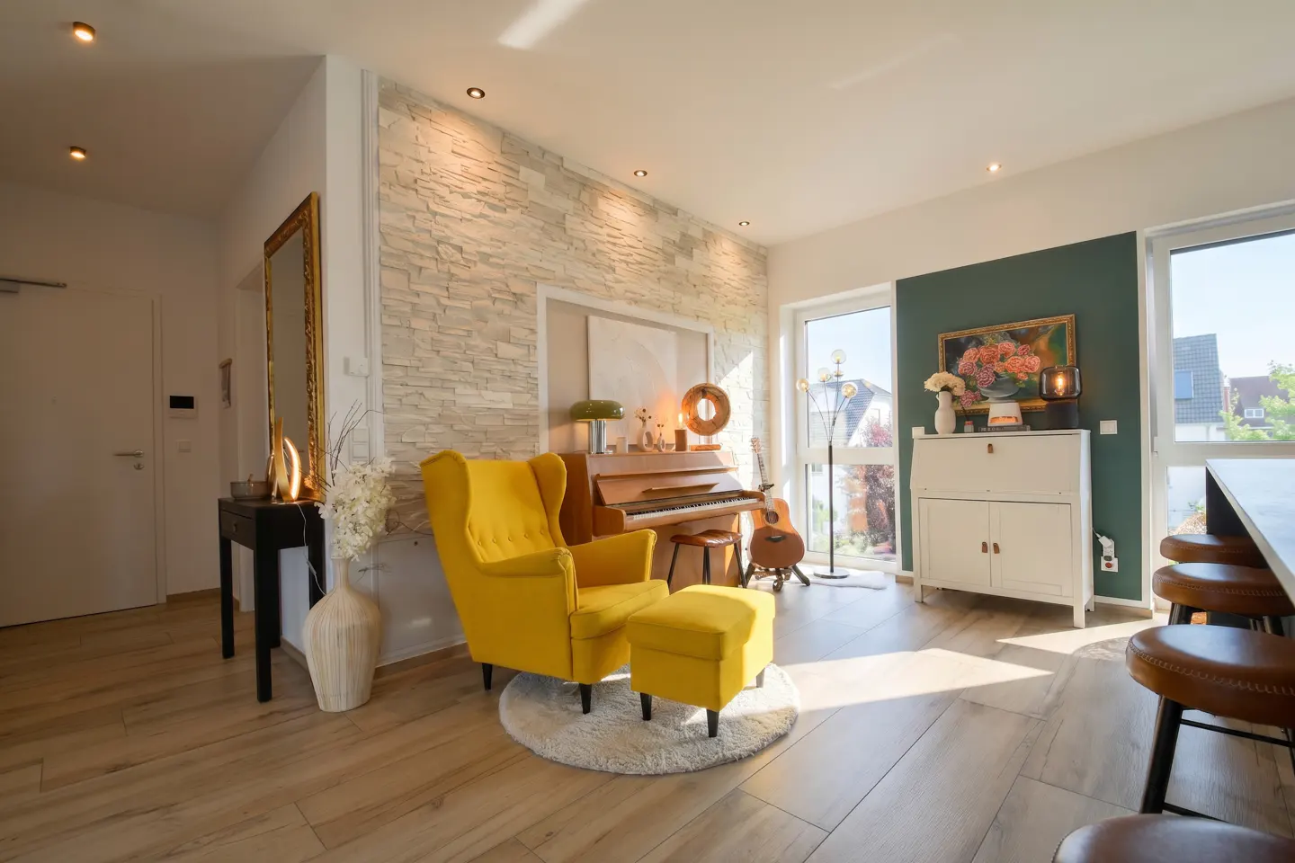 Bright living room with a yellow armchair, piano, guitar, and white cabinet. Sunlight streams through the windows.