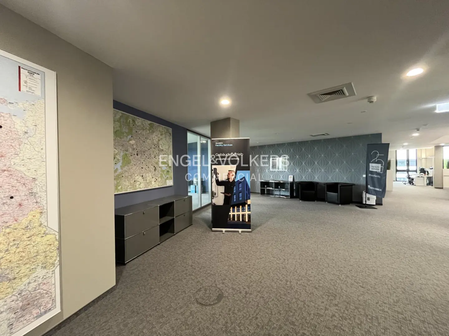 Engel & Volkers commercial office space with gray carpet, black chairs, and a large map on the wall.