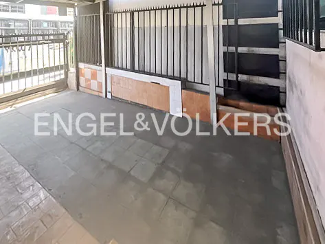 A gray tiled patio with a black metal fence and an Engel & Völkers logo.