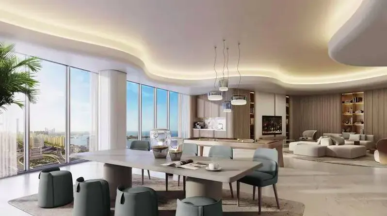 Bright, modern living space with a dining table, pool table, and ocean view from large windows. Neutral tones and recessed lighting.