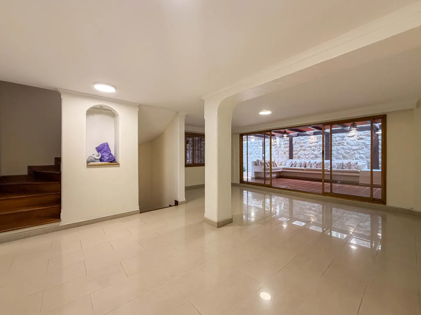 A bright, empty room with tile floors, white walls, and a large sliding glass door to an outdoor patio.