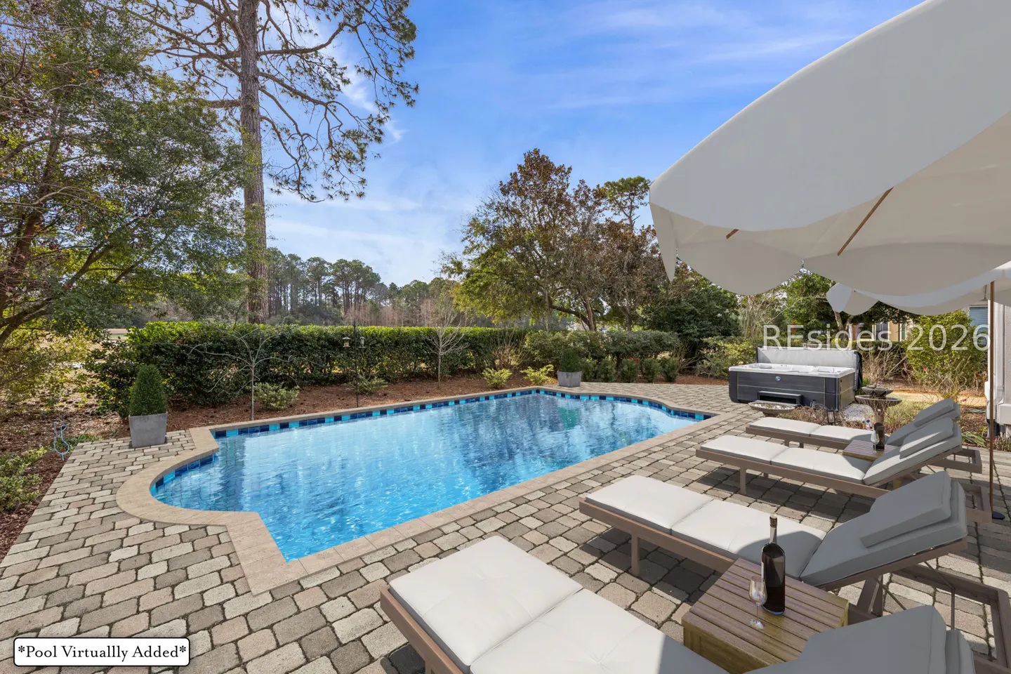 Outdoor pool area with lounge chairs, a hot tub, and a large white umbrella on a sunny day.