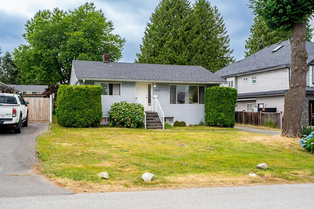 Single-story light blue house with a front lawn, white door, and a driveway with a white pickup truck.