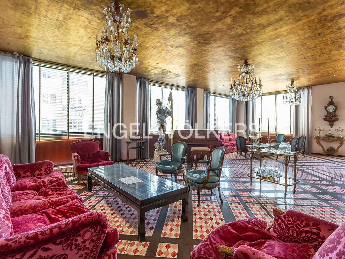 Luxurious living room with a gold-leaf ceiling, crystal chandeliers, red velvet furniture, and a checkered tile floor.