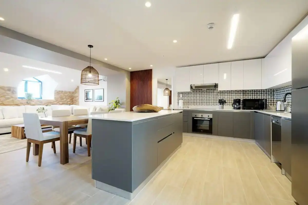 Open-concept kitchen and living area with gray island, white cabinets, and wood dining table.
