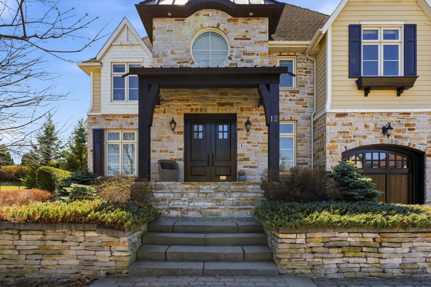 Stone house with black door and pergola. Steps lead up to the entrance. Number 12 is visible.