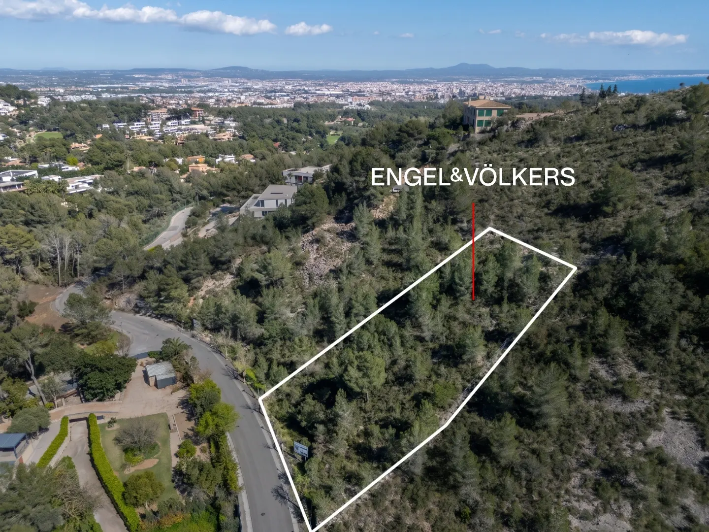 Aerial view of a wooded lot outlined in white, with Engel & Völkers logo, against a city and ocean backdrop.
