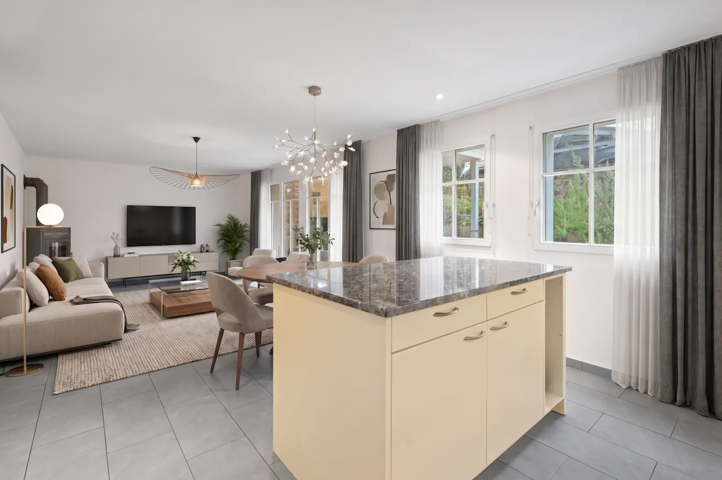 Open-concept living space with a kitchen island, dining table, sofa, and TV. The room has gray tile floors and white walls.
