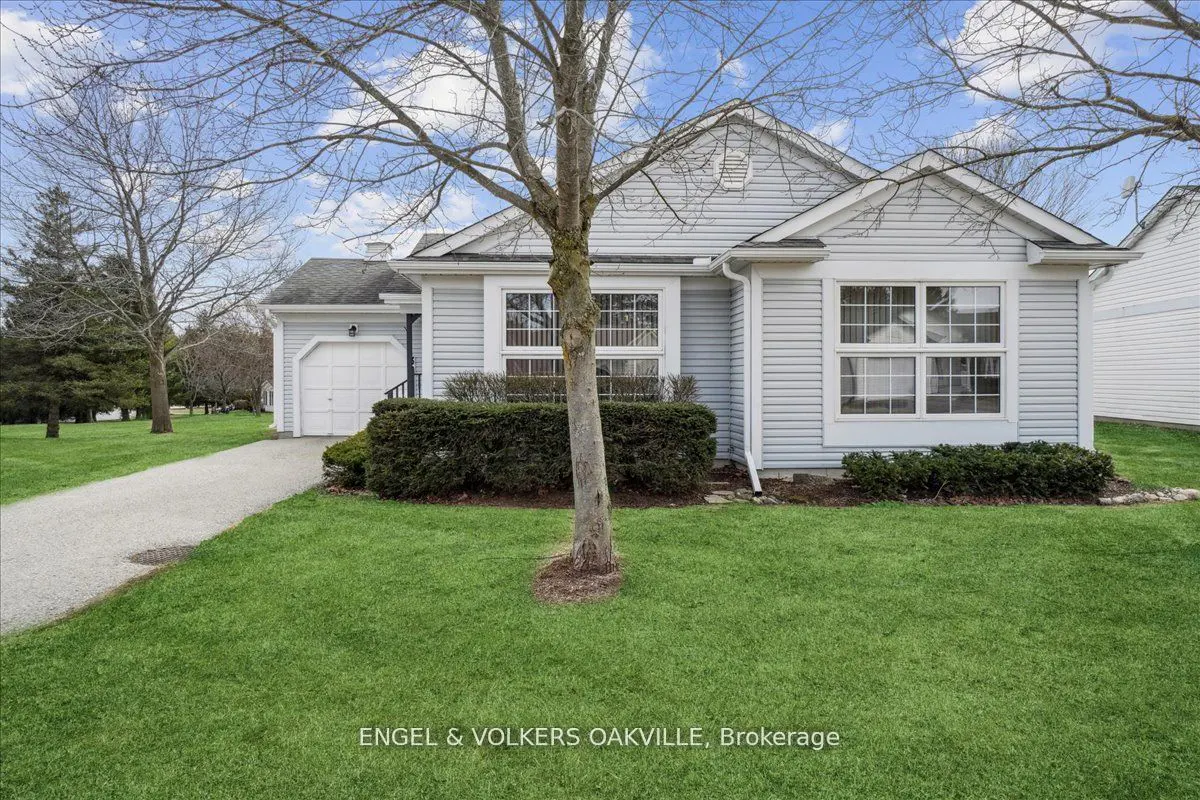 A light blue single-story house with a white garage door, green lawn, and a tree in front.