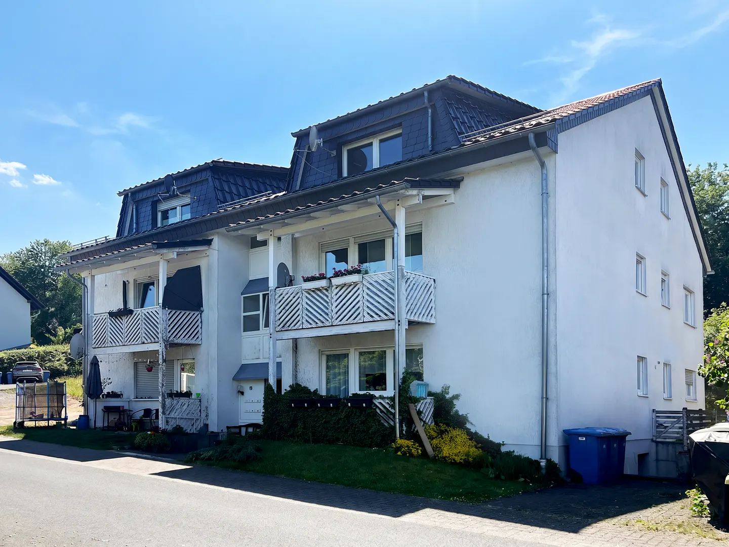 Exterior view of a white two-story apartment building with dark gray roof and white balconies.