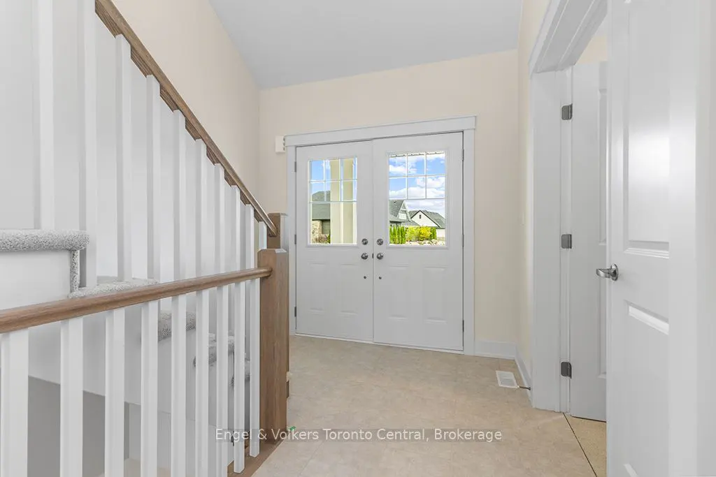 Bright foyer with white double doors, a staircase with white railings and wood trim, and a white door to the right.