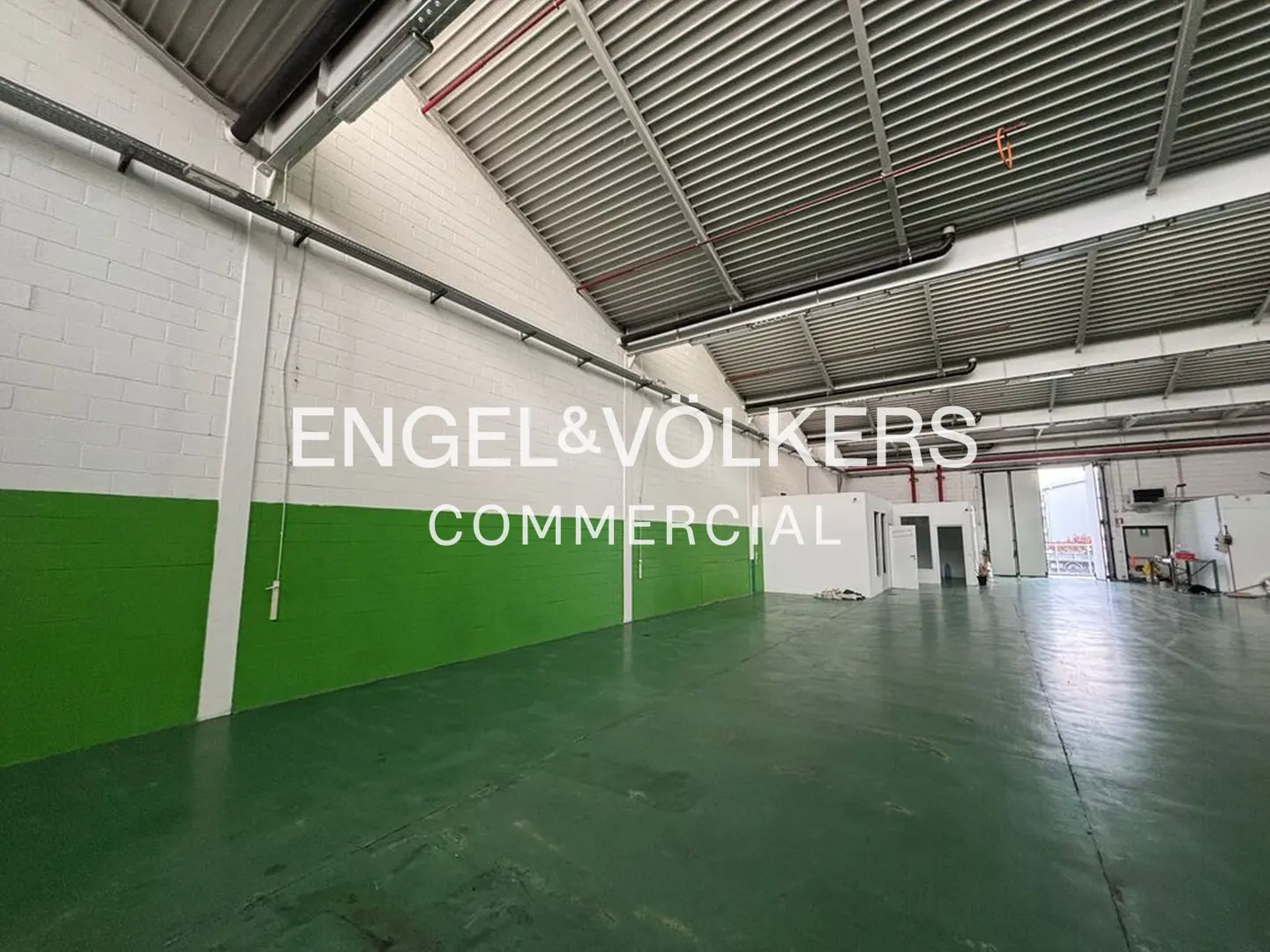 An empty warehouse with green floors and white walls with green trim.