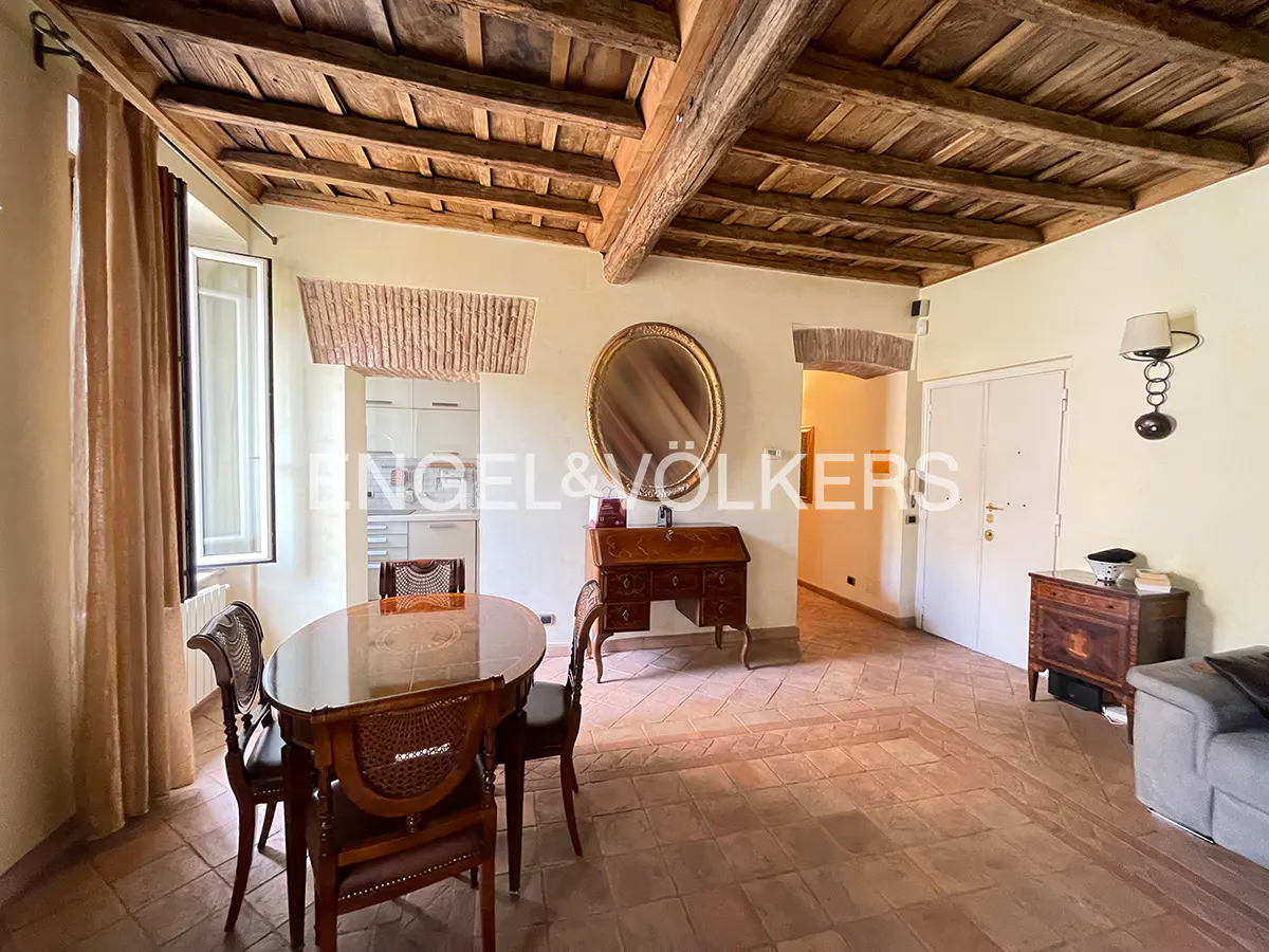 A dining room with wooden beams, a table with chairs, and a mirror on the wall.