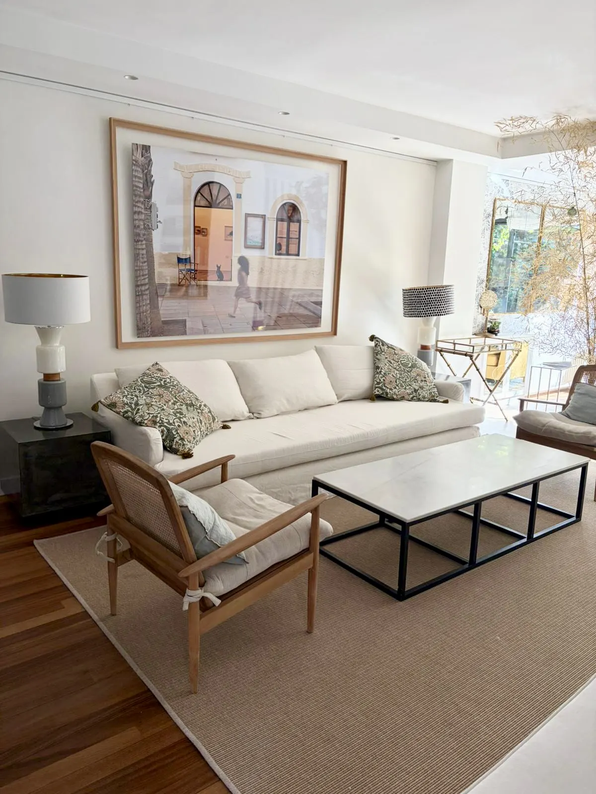 Bright living room with a white sofa, a marble coffee table, and a framed picture above the sofa.
