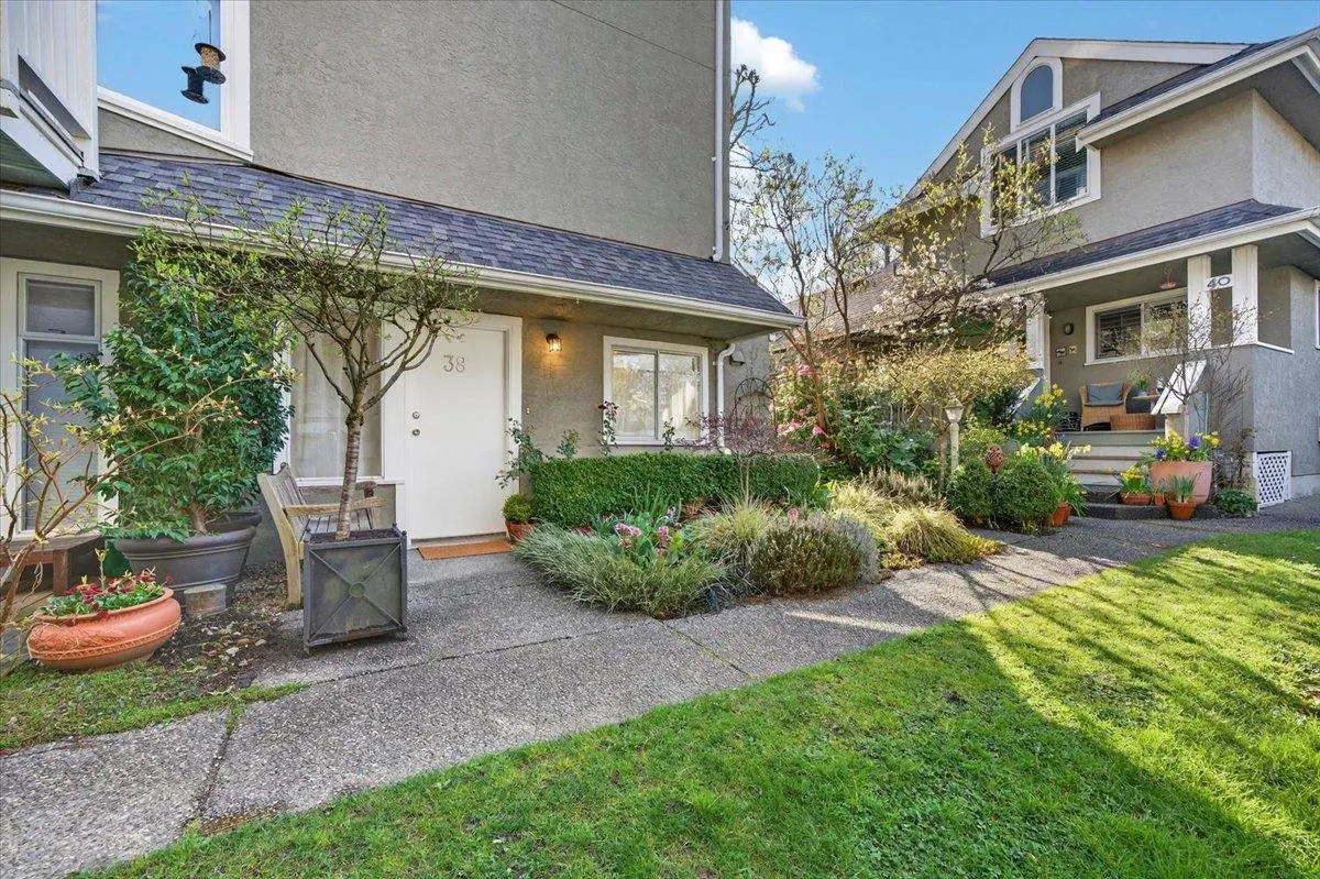 Exterior view of a gray townhouse with a white door, number 38, and a landscaped front yard.