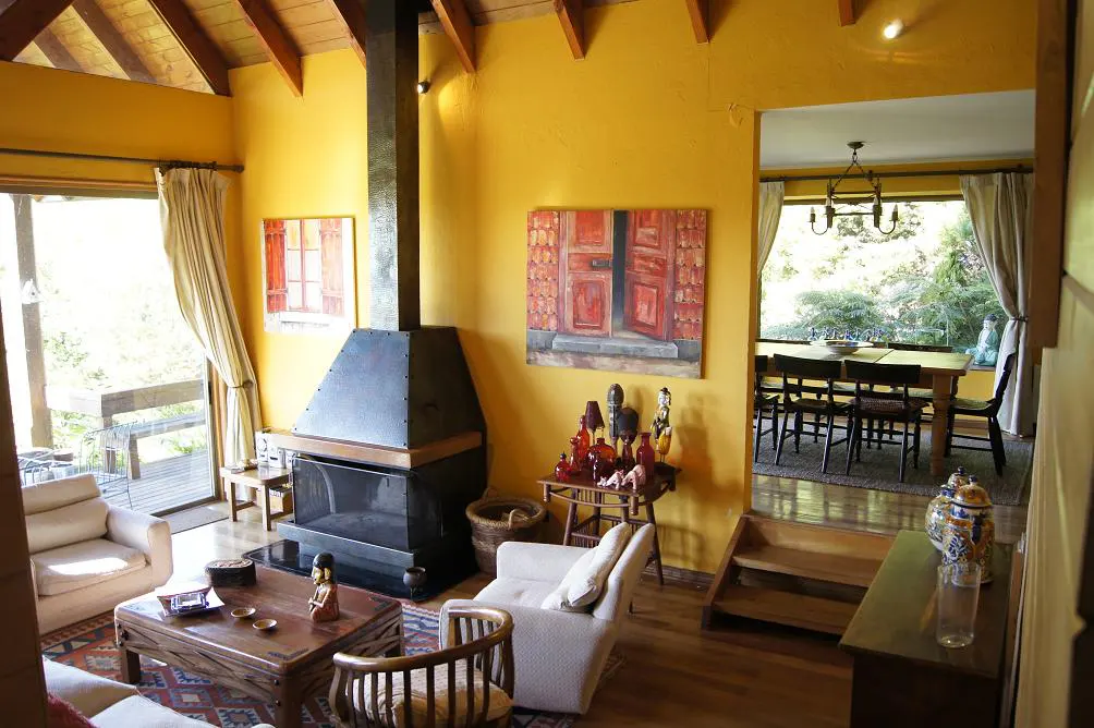 A living room with yellow walls, a black fireplace, and a wooden coffee table. A dining room is visible through an archway.