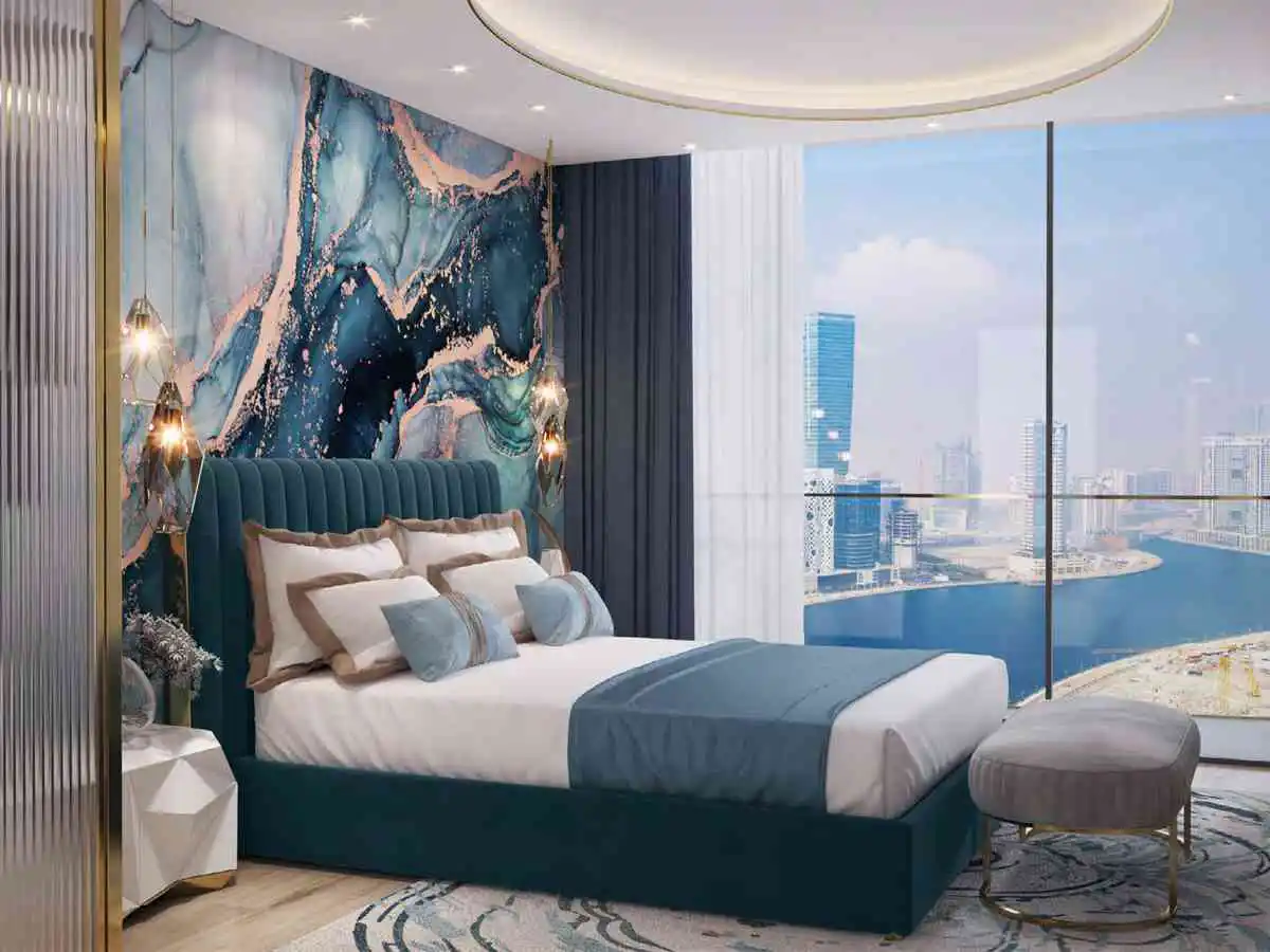 A modern bedroom with a teal bed, marble wallpaper, and a large window overlooking a city skyline.