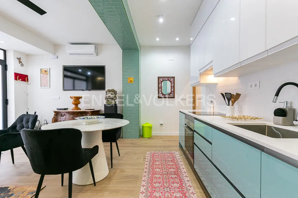 Modern kitchen with light blue cabinets, white countertops, a marble dining table, and black chairs on wood flooring.