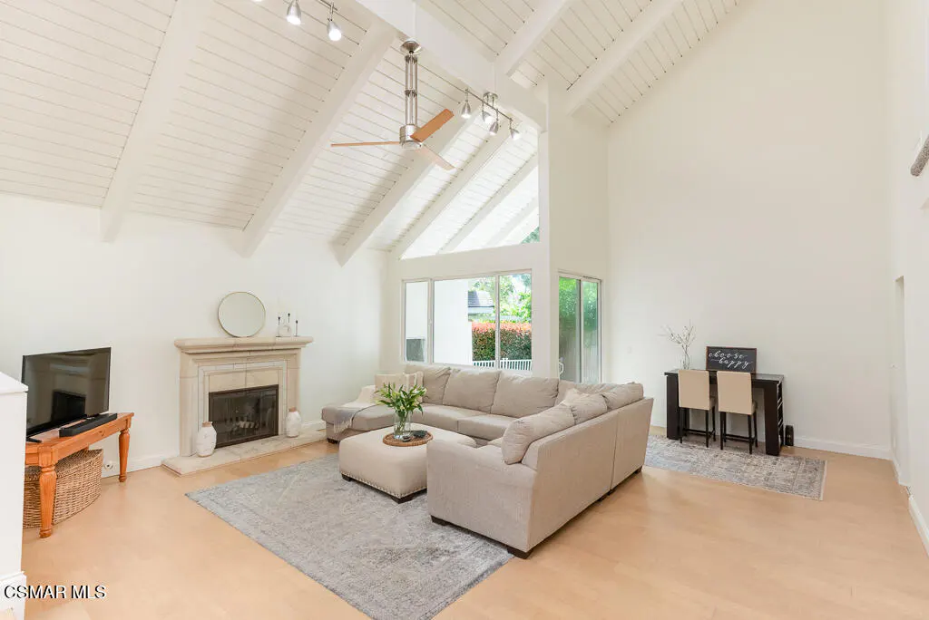 Bright living room with vaulted ceilings, a beige sectional sofa, fireplace, and a desk with two chairs.