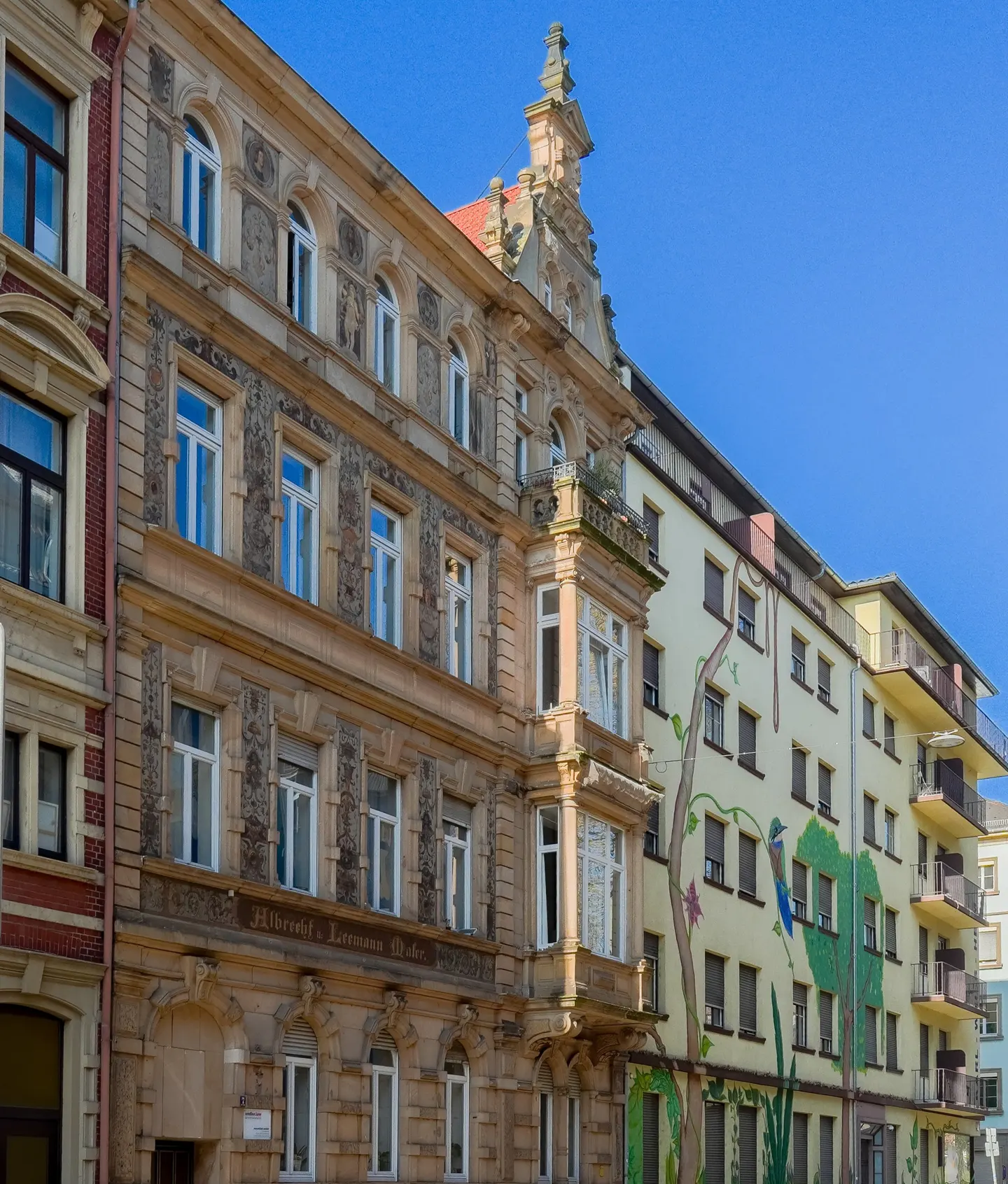 A street view of ornate, multi-story buildings with white windows under a clear blue sky.