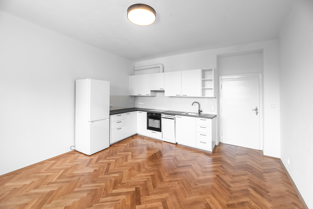 Modern kitchen with white cabinets, stainless steel appliances, and a white refrigerator on a herringbone wood floor. [AI-generated text]