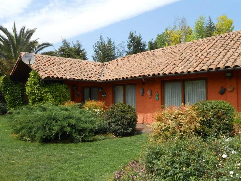 Exterior of an orange house with a terracotta tile roof, green lawn, and lush landscaping.