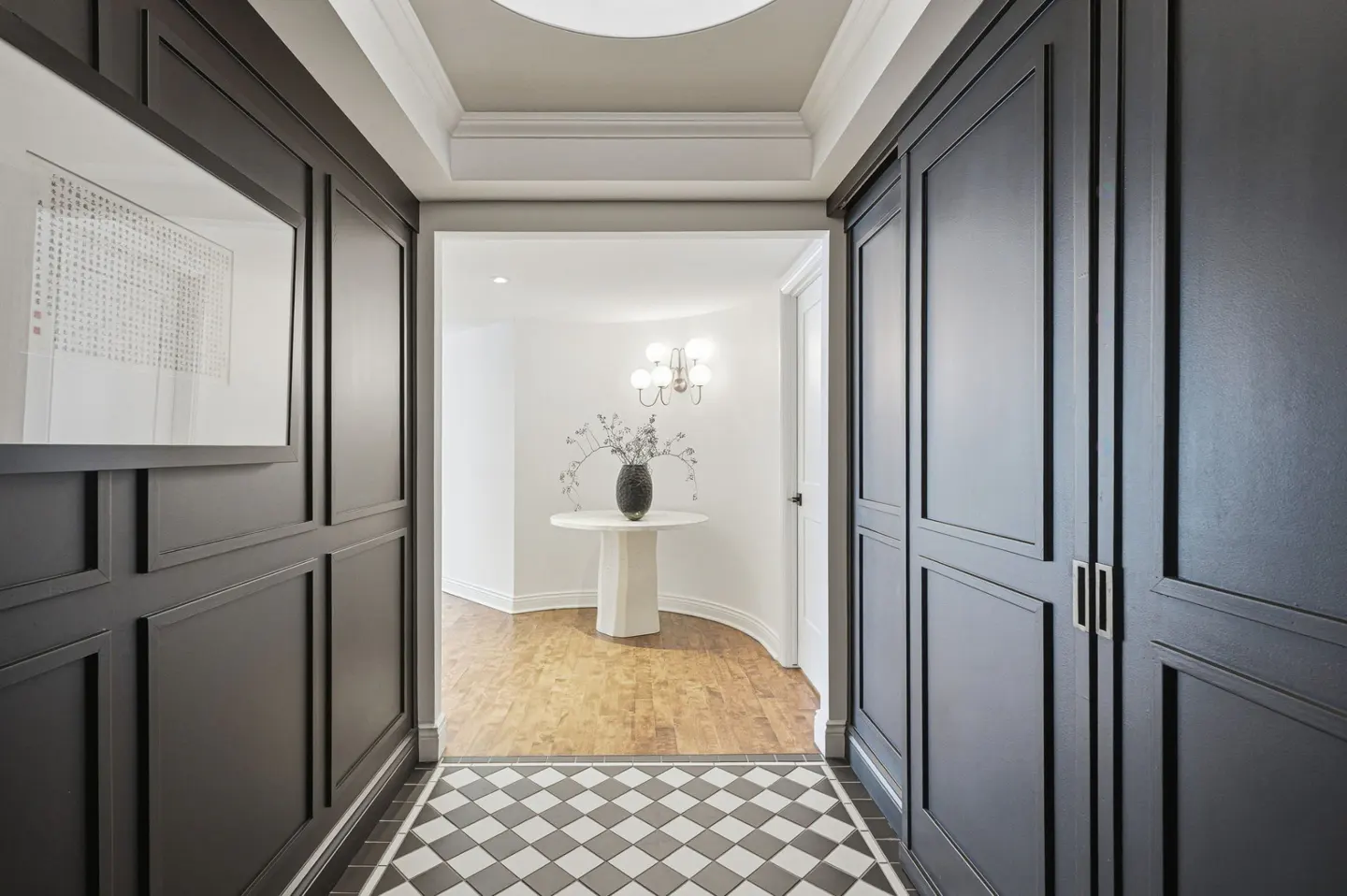 Hallway with black and white checkered floor, dark gray walls, and a white table with a vase in the background.