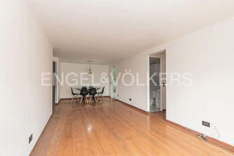Bright, empty room with hardwood floors, white walls, and a black dining set. A bathroom is visible through a doorway.