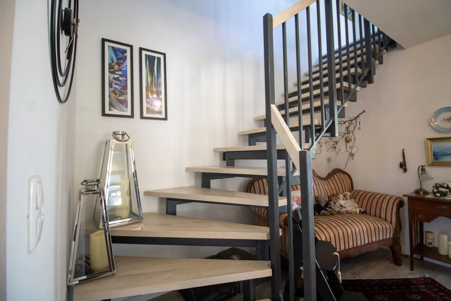 Interior view of a staircase with light wood steps and black metal railings, leading to the upper floor of a home.