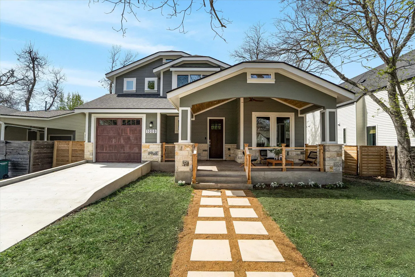 Two-story house with a brown garage door, a green porch, and a stone walkway.