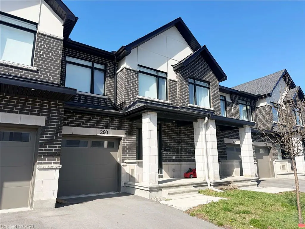 Exterior of a modern, two-story townhouse with dark brick, white trim, and a gray garage door. The house number "260" is visible above the garage.