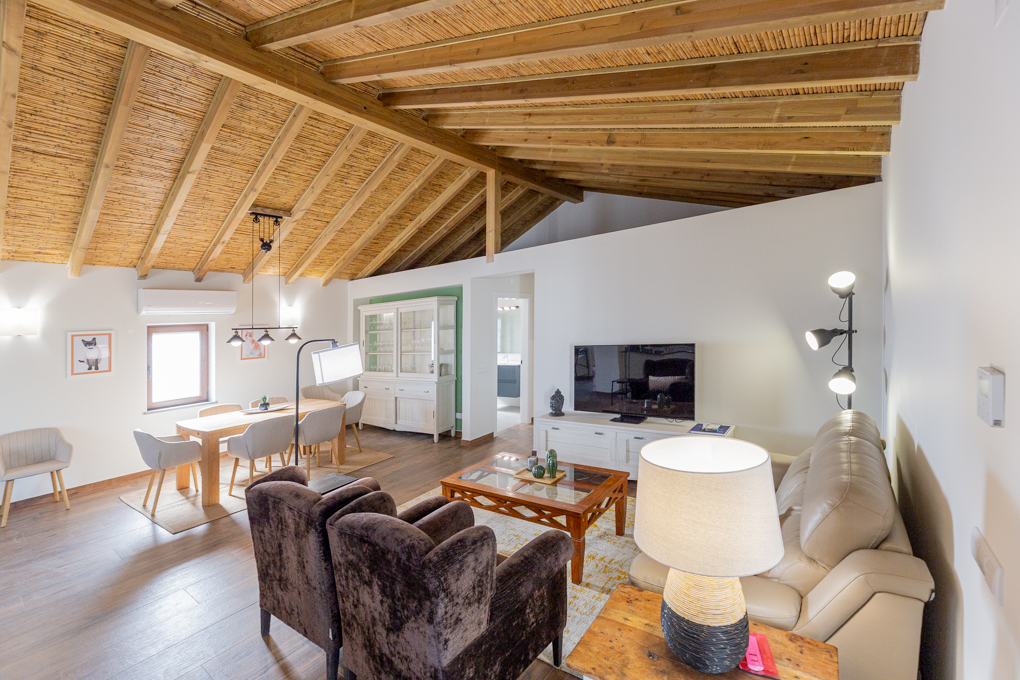 Bright living room with a straw ceiling, brown chairs, a beige sofa, and a dining table with chairs.
