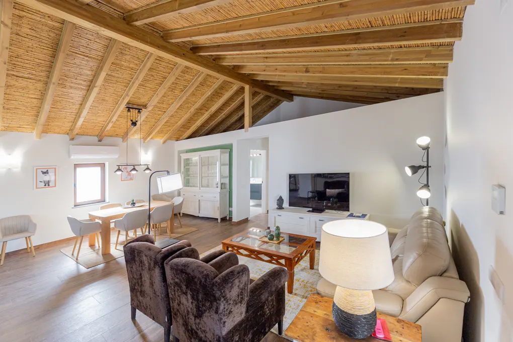 Bright living room with a straw ceiling, brown chairs, a beige sofa, and a dining table with chairs.