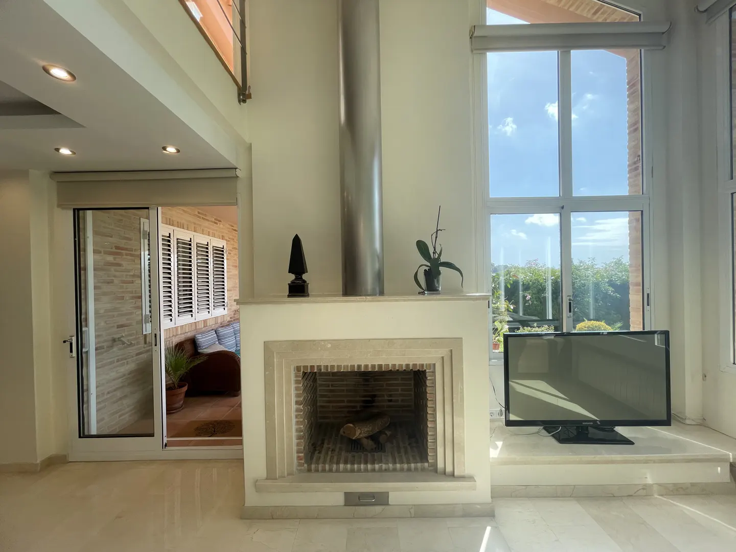 Bright living room with a fireplace, a TV, and a sliding door to a patio with a blue couch.