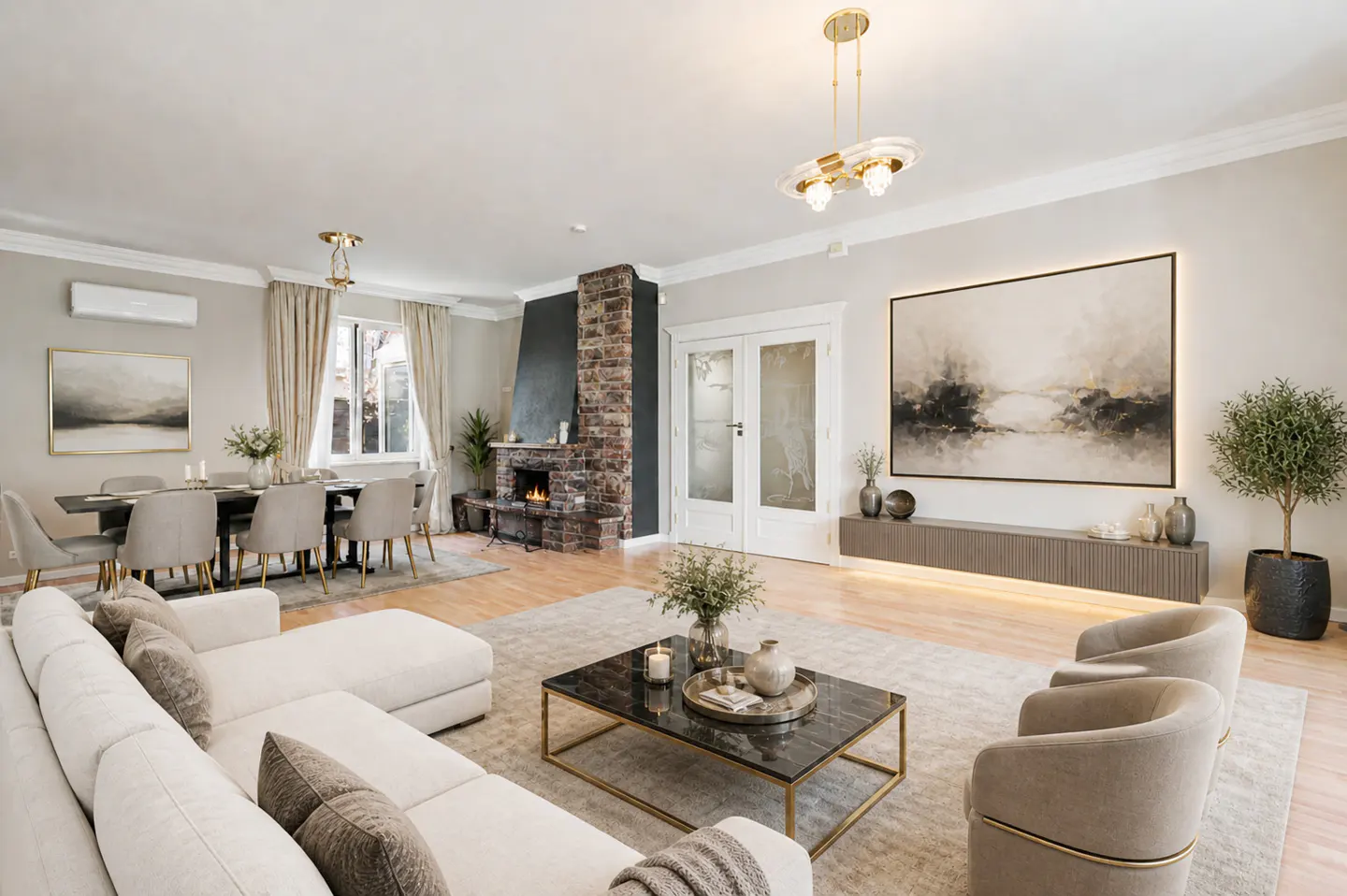 A bright living room with a white sofa, two beige chairs, a fireplace, and a dining table.