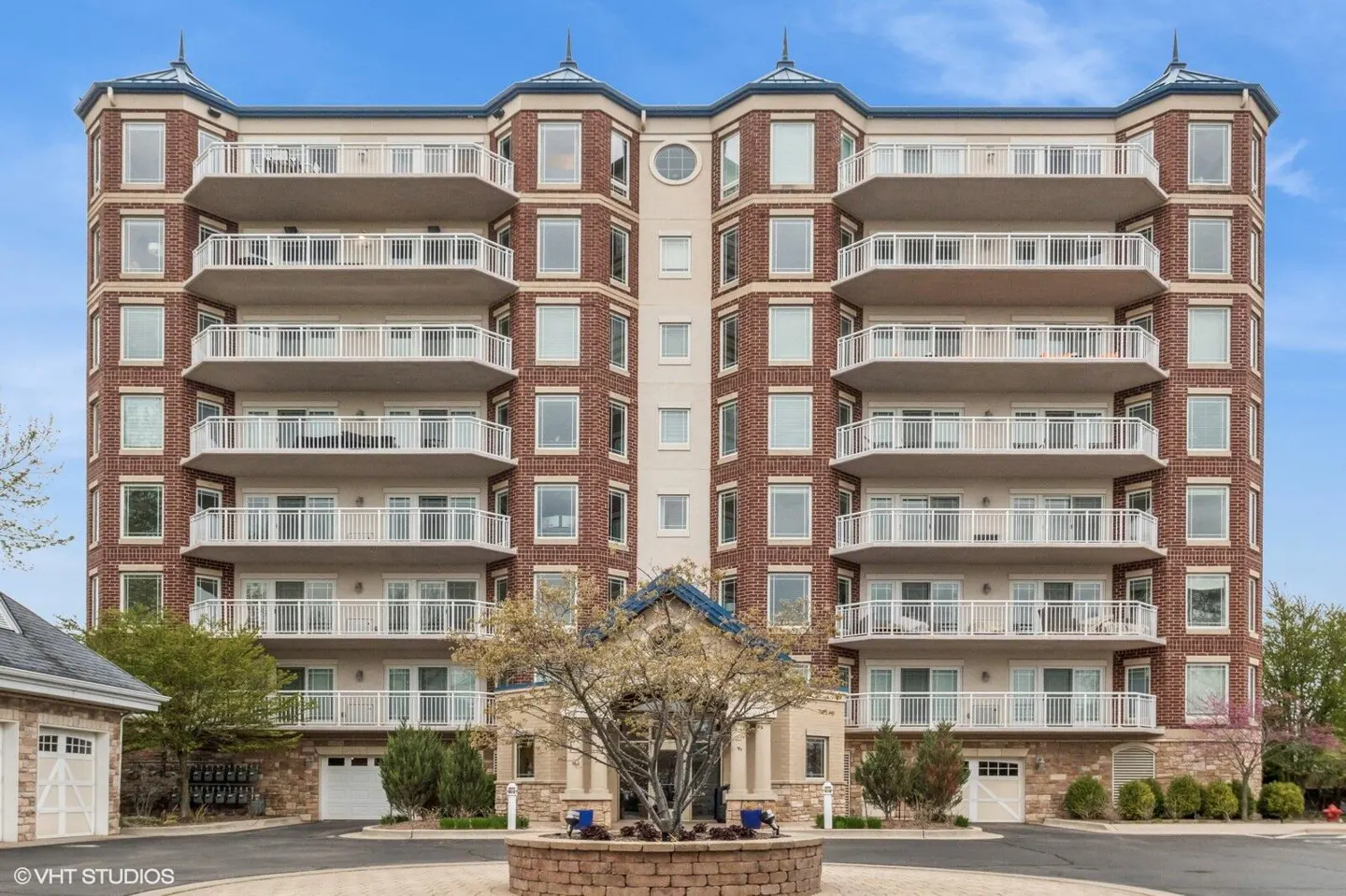 Exterior of a brick apartment building with white balconies and a blue roofed entrance.