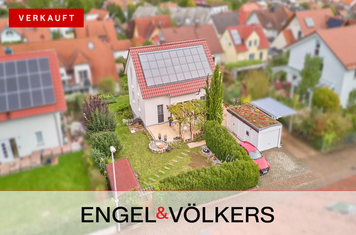Aerial view of a sold, two-story house with solar panels, a green lawn, and a red car parked in the driveway.