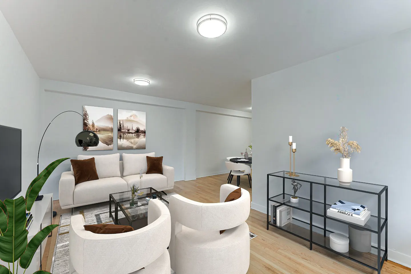 Living room with white sofa, chairs, and light blue walls. Artwork and a black console table add detail.