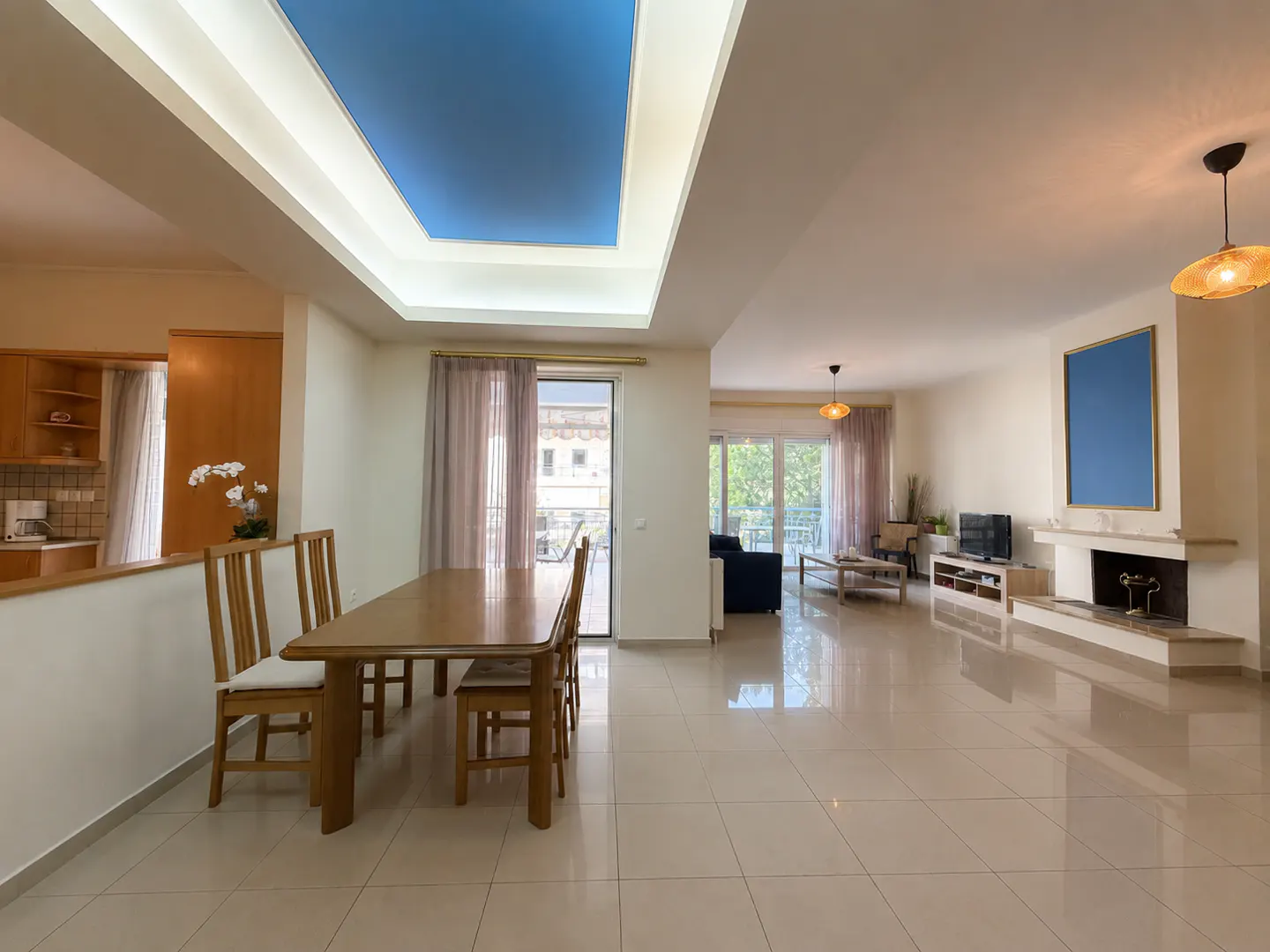 Open-concept living and dining area with tile floors, a blue ceiling panel, and a fireplace.