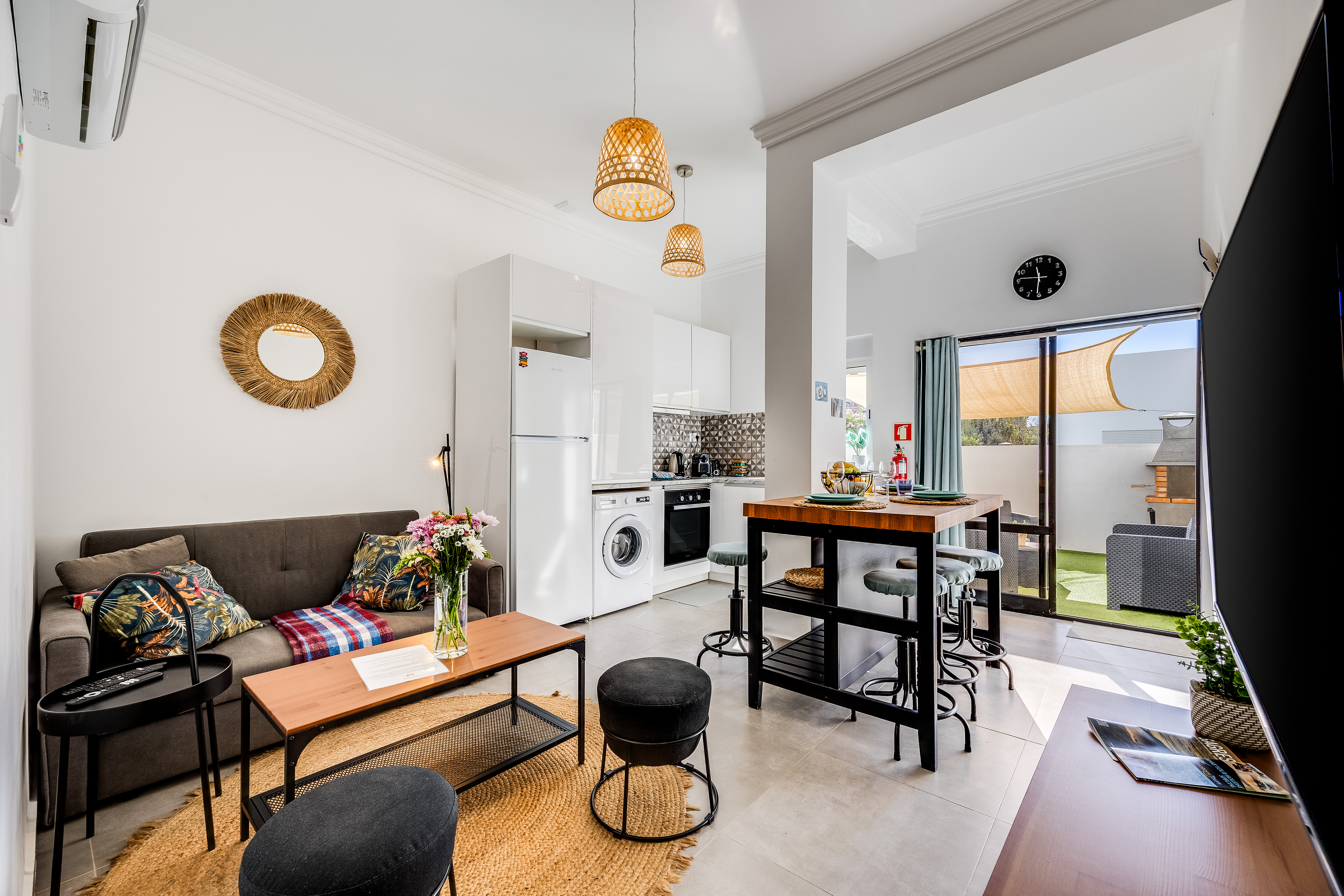 Modern open-plan apartment with a grey sofa, wooden coffee table, kitchen area, and a dining island with stools. [AI-generated text]